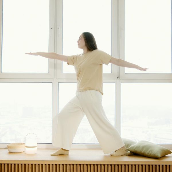 Woman practicing a calm yoga pose indoors near a window.